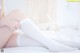 A woman in white stockings sitting on a bed.