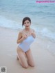 A woman in a white bathing suit sitting on the beach.