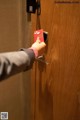 A person opening a door with a red card in their hand.