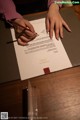 A woman signing a document with a pen on a table.