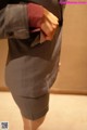 A woman in a gray suit is holding a cell phone in her pocket.