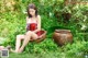 A woman in a red dress sitting in a bowl in the grass.