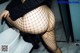 A woman in fishnet stockings is standing in a bathroom.