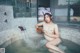 A naked woman sitting in a bathtub with a bowl of water.