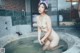 A naked woman sitting in a hot tub with a cat ears headband.