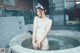 A naked woman sitting in a hot tub with a cat ears headband.