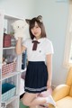 A woman in a school uniform holding a stuffed animal.