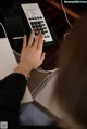 A woman is typing on a telephone at a desk.