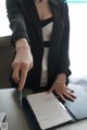 A woman in a business suit holding a pen and signing a document.