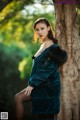 A woman leaning against a tree in a forest.