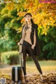 A woman standing next to a suitcase in a park.