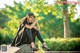 A woman sitting on a stone wall in a park.