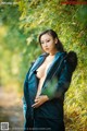 A woman in a blue coat standing in front of a bamboo tree.