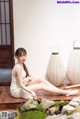 A woman in a white dress sitting on a wooden floor.