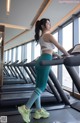 A woman is running on a treadmill in a gym.