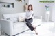 A woman sitting on a white couch in a living room.