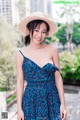 A woman in a blue dress and a straw hat posing for a picture.