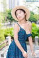 A woman in a blue dress and straw hat posing for a picture.