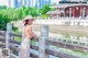 A woman in a white dress and straw hat standing on a bridge.