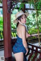 A woman in a blue dress and a straw hat posing for the camera.