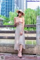 A woman in a white dress and straw hat posing for a picture.