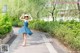 A woman in a blue dress and straw hat dancing in a park.