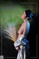 A woman in a white kimono holding a bunch of wheat.