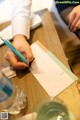 A person writing on a piece of paper with a pen.