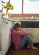 A woman sitting on the floor in a kitchen next to a stove.