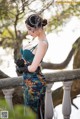 A woman in a green dress and black gloves standing on a railing.