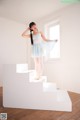 A young ballerina standing on a set of stairs in a room.