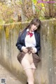 A woman in a school uniform leaning against a wall.