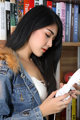 A woman holding a remote control in front of a book shelf.