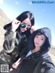 A couple of women standing next to each other on top of a mountain.