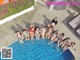 A group of women in bikinis sitting around a swimming pool.