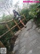 A woman standing on a stone path next to a wooden fence.