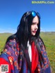 A woman with long black hair wearing sunglasses and a colorful shawl.