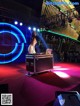 A woman standing on top of a stage next to a laptop computer.