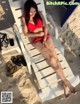 A woman in a red bikini sitting on a beach chair.