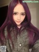 A woman with long purple hair is posing for a picture.