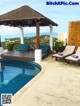 A gazebo next to a swimming pool with lounge chairs.