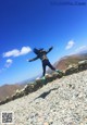 A woman jumping in the air on top of a mountain.