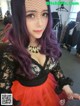 A woman with purple hair wearing a black and red dress.