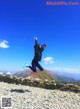 A person jumping in the air on top of a mountain.