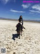 A woman riding on the back of a horse in the desert.