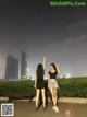 A couple of women standing next to each other on a sidewalk.