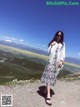 A woman standing on top of a mountain with mountains in the background.