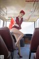 A woman in a red uniform is sitting on a bus.