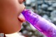 A close up of a person licking a purple dildo.