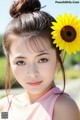 A young woman holding a sunflower in her hair.